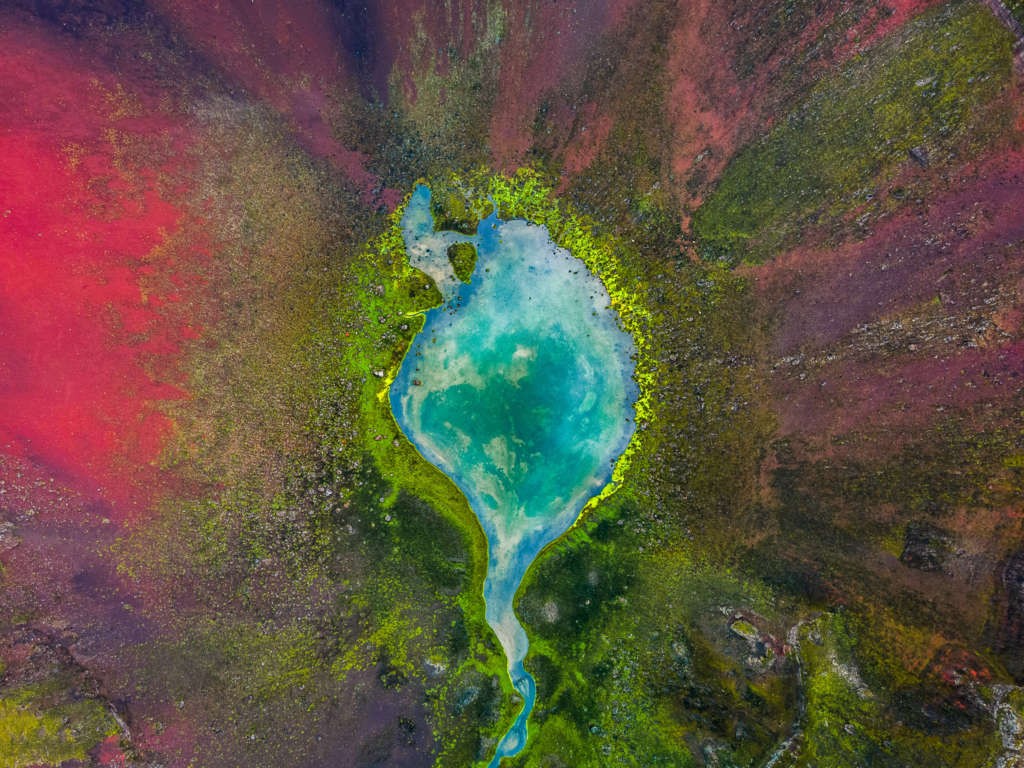 Photo of a small lake in a colorful volcanic crater taken from up above with a drone. Raudibotn a gem in the highlands.