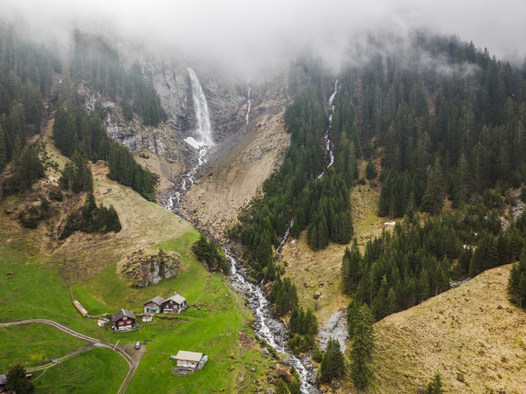 Drone shot of the Stäubifall waterfall, with some huts in the foreground
