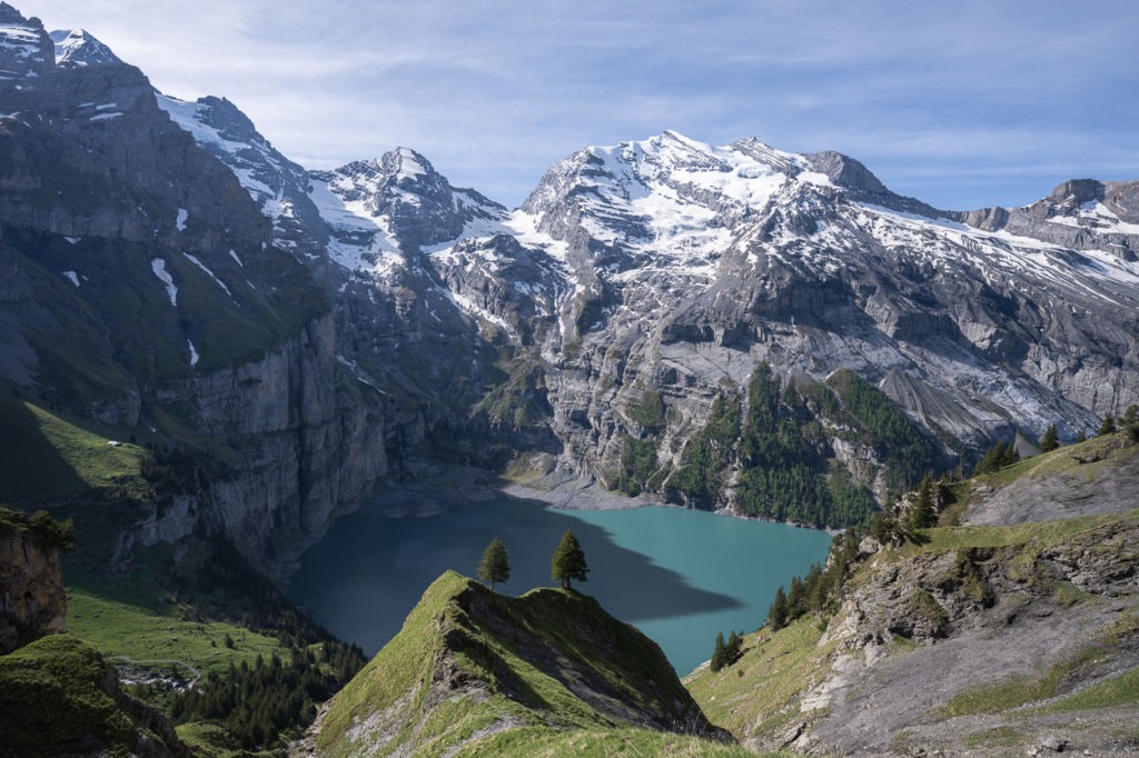 The Oeschinensee hike and the iconic view of two lone tress against the lake surrounded by the mountains in an Idyllic alpine scenery