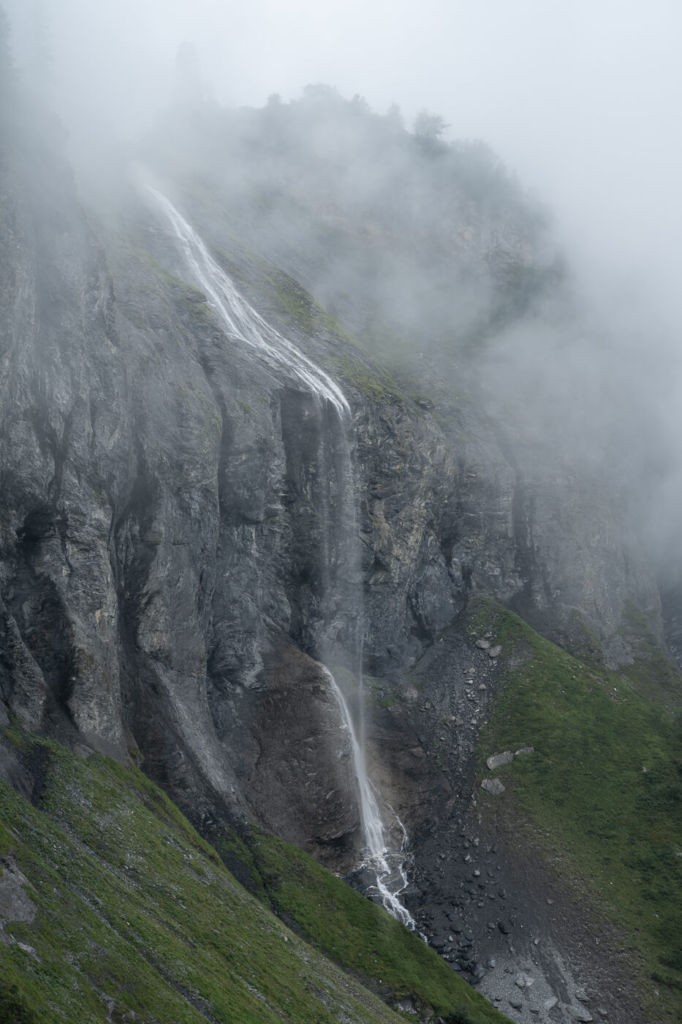 A waterfall falling from a cliff on a foggy day
