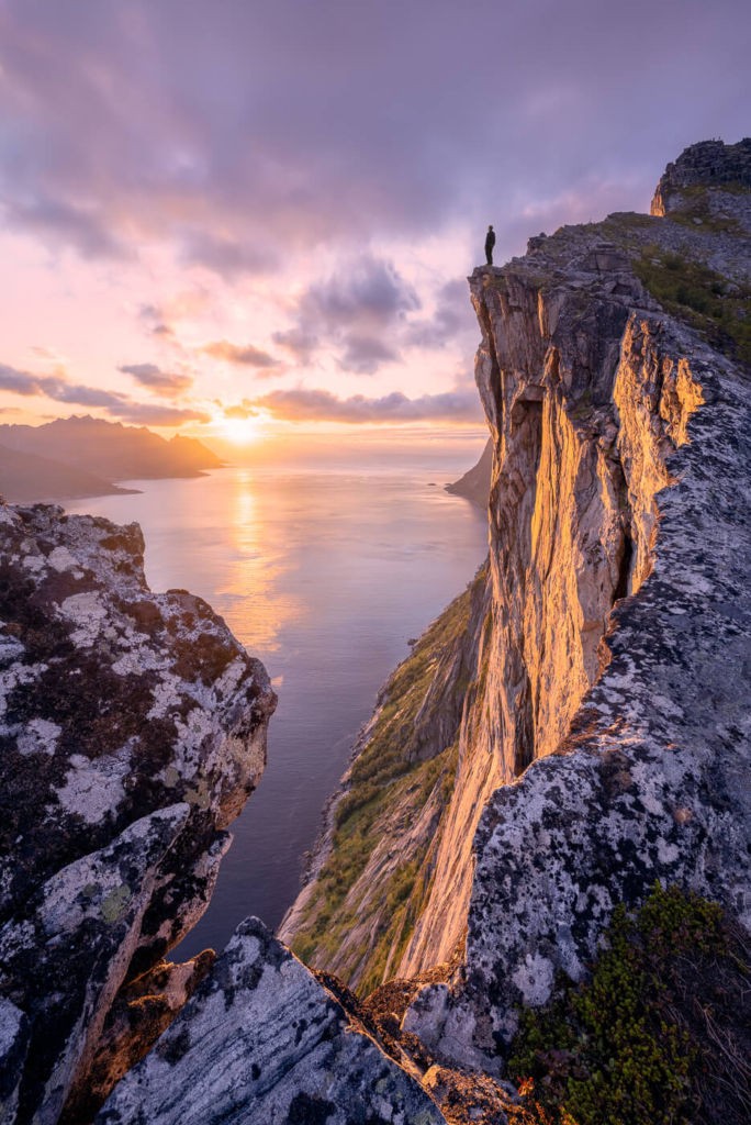 Hiker watching the sunset from a cliff in a Norwegian fjordno the trail to Hesten