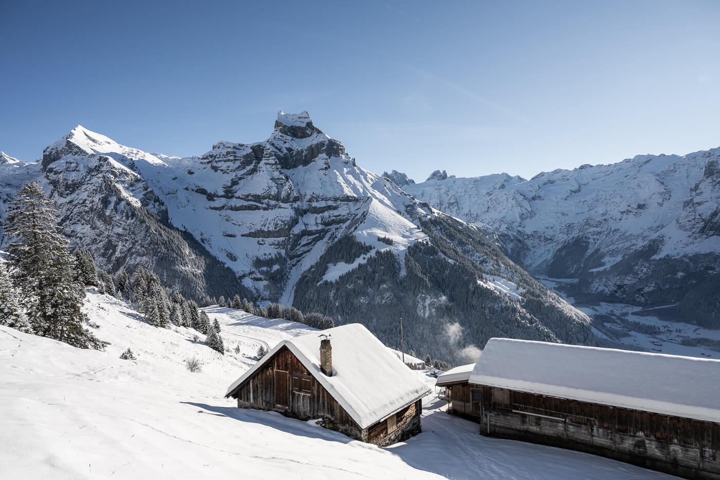 Snowshoeing in Engelberg Ristis, huts along the trail with snowy mountains in the background.