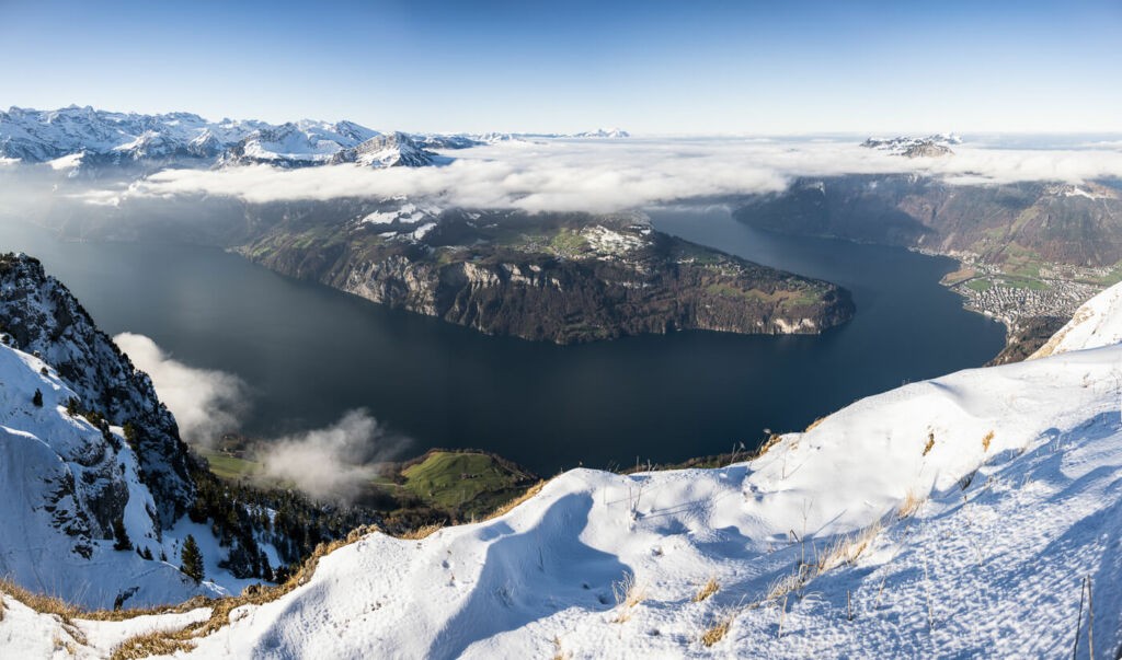 Panoramic image of lake Lucerne surrounded by snow capped mountains on a sunny winter day