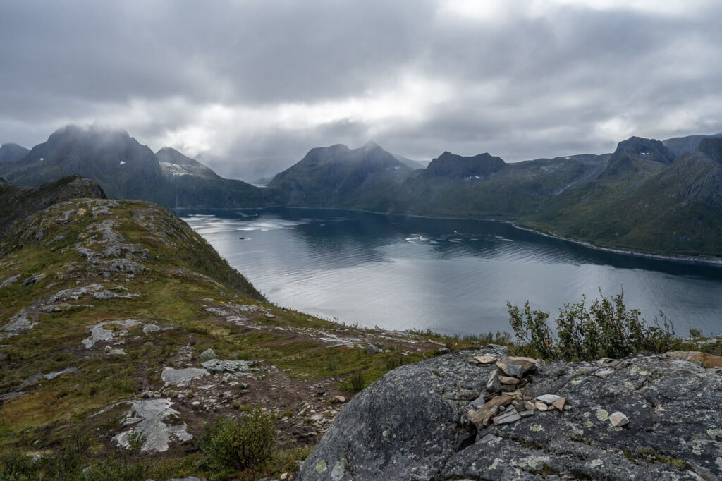 View of a fjord on the island of Senja in Norway on a cloudy day, with steep mountains in the background