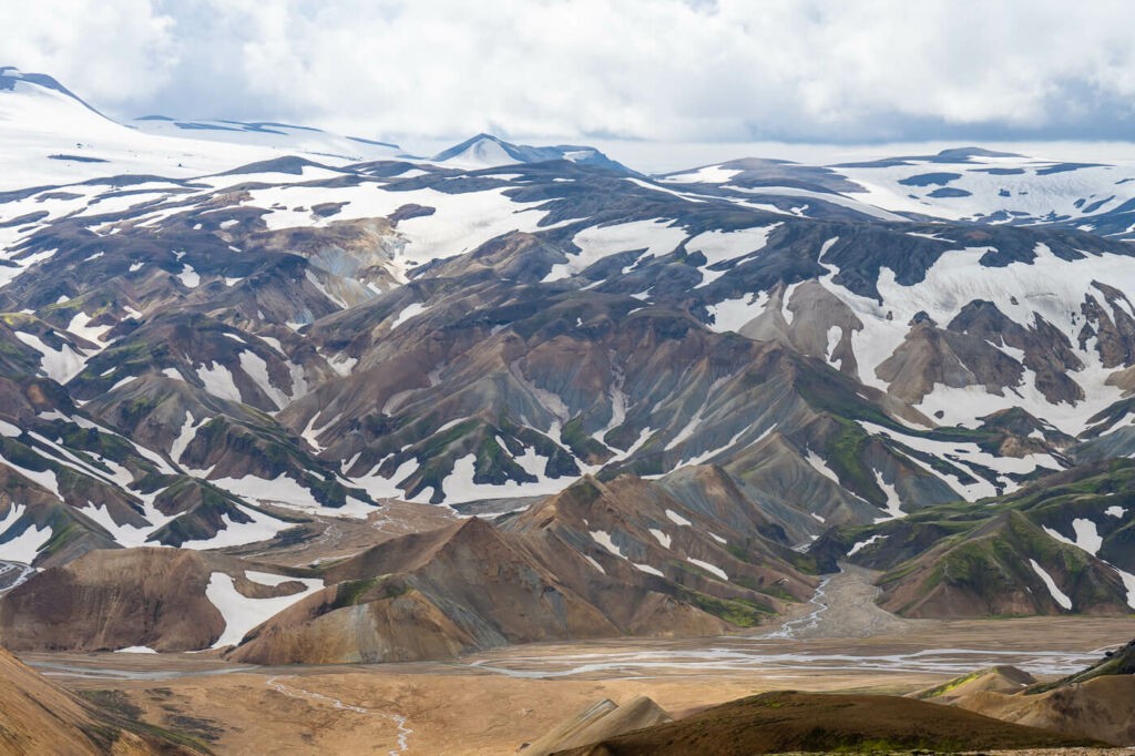 View of colourful Rhyolite mountains partially covered in snow on the Skalli trail in Landmannalaugar
