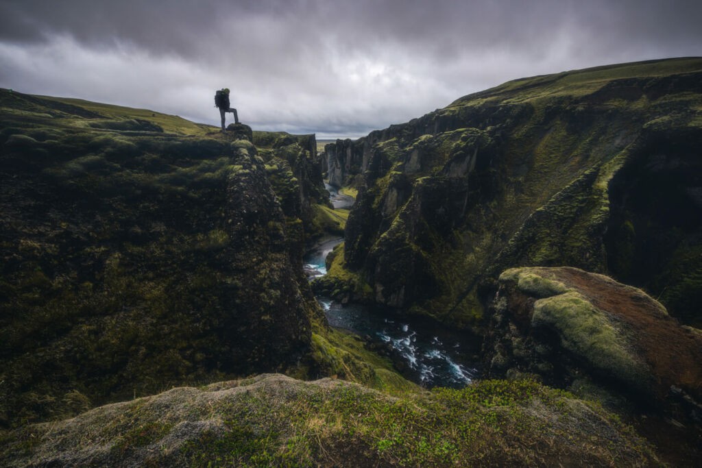 Hiker on the cliffs of the Fjaðrárgljúfur Canyon during a hike in Iceland