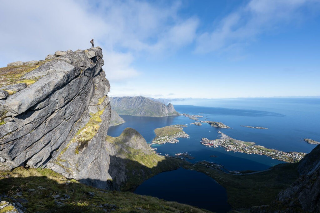 Hiker looking at the landscape from the top of a rock on the Lofoten islands on the trail to Veinestinden