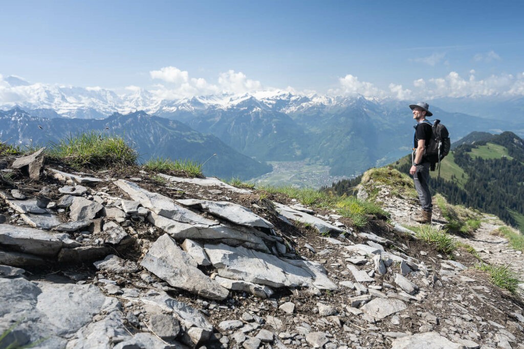Hiker with a hat watching the panorama from the summit of the Suggiture mountain on a hike in Switzerland.