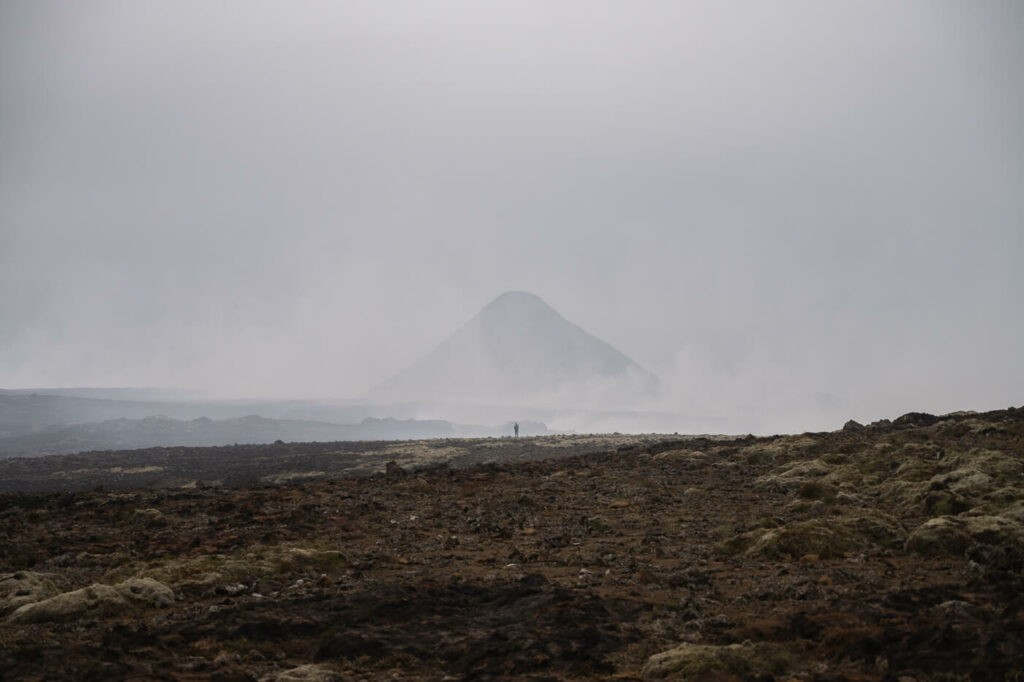 Hiker walking on a burnt moss field at the 2023 volcanic eruption of Frgradalsfjall