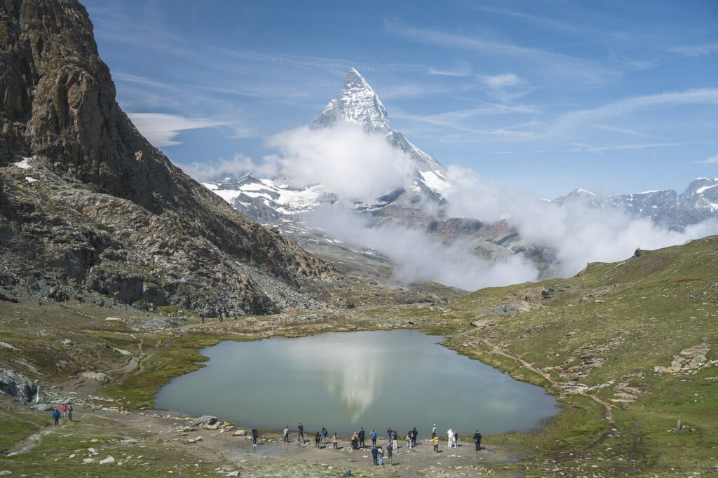 People looking at the Matterhorn reflecting into the Riffelsee while hiking to the gornergrat.