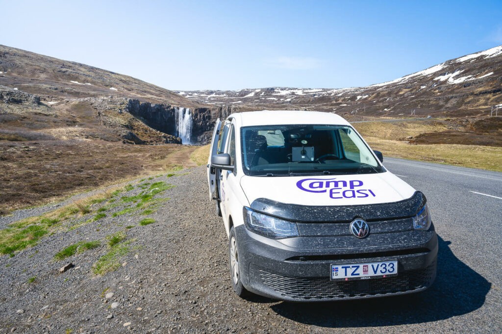 Image of a camper van parked next to a waterfall in Iceland during a road trip.