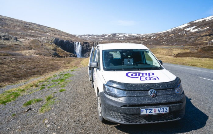 Image of a camper van parked next to a waterfall in Iceland during a road trip.