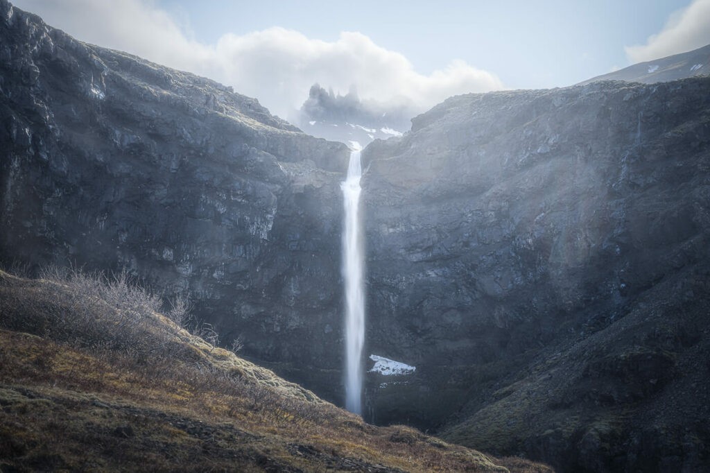 Flogufoss waterfall in the east of Iceland with mountains in the background.