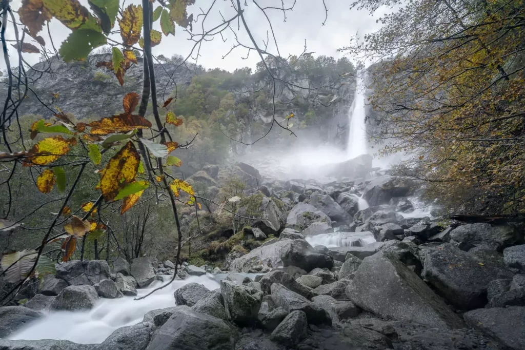 Cascata di Foroglio viewed from the rocks next to the river banks and colorful autumn leaves