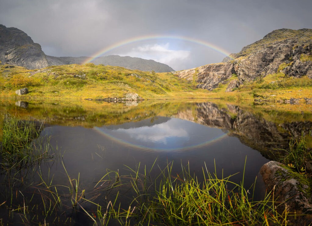 rainbow reflecting in a large puddle in the Norwegian mountains on the Munken Hiking Trail