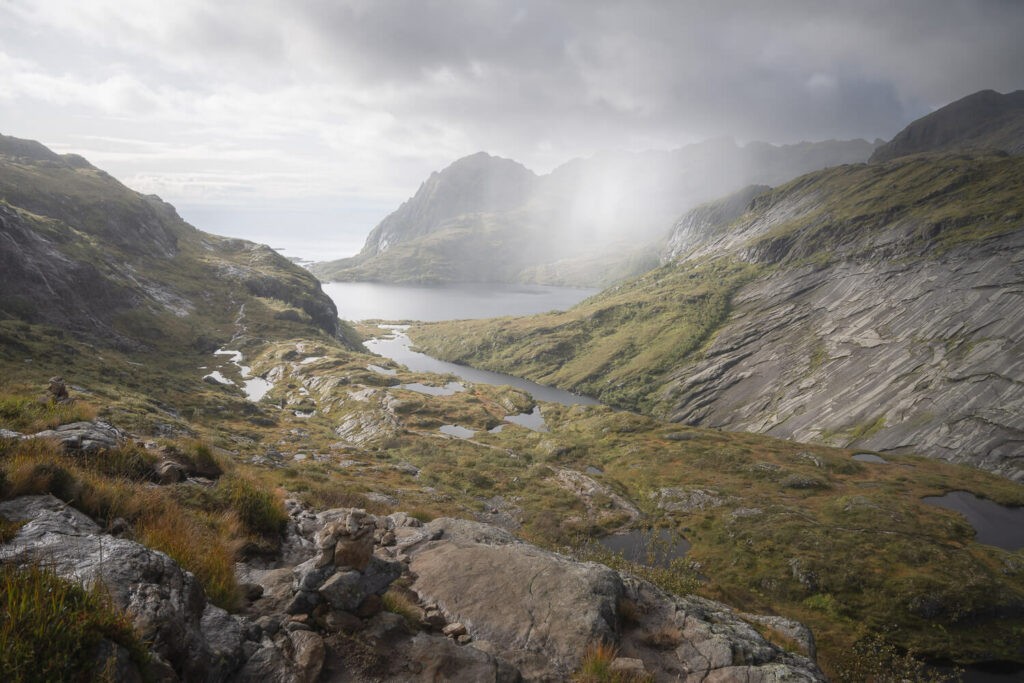 A rainshower can be seen in the distance in the rugged lofoten landscape on the hike to munken