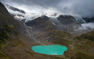 the blue waters of the Steinsee lake and Steingletscher, a glacier in the background on a cloudy day in the Swiss alps.