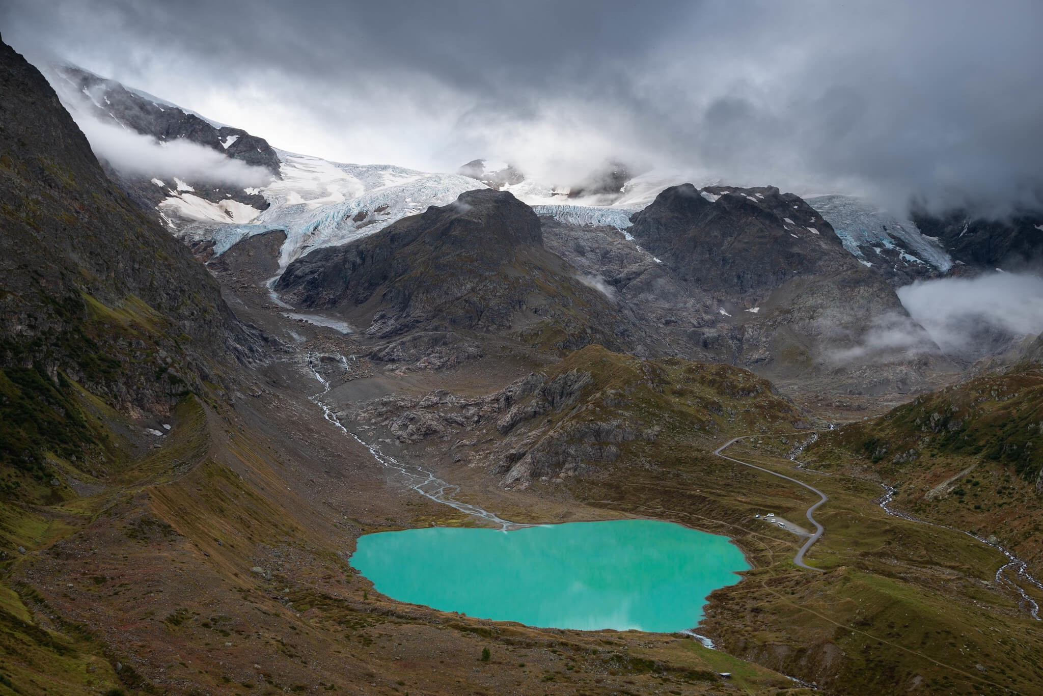the blue waters of the Steinsee lake and Steingletscher, a glacier in the background on a cloudy day in the Swiss alps.