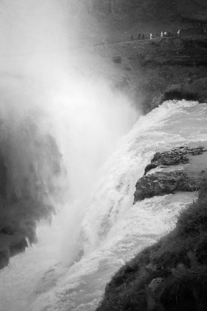 black and white photo of gullfoss with some people behind it