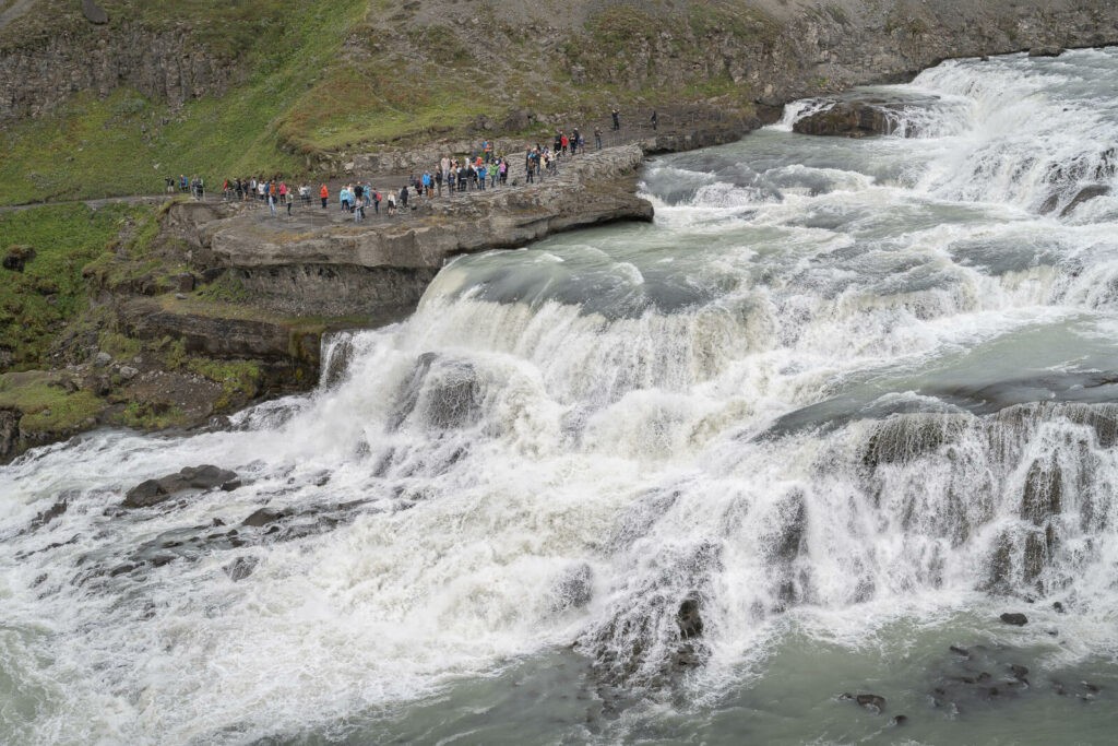 View of the east side of Gullfoss at the end of the hike. Several people can be seen on a rock on the opposite side.