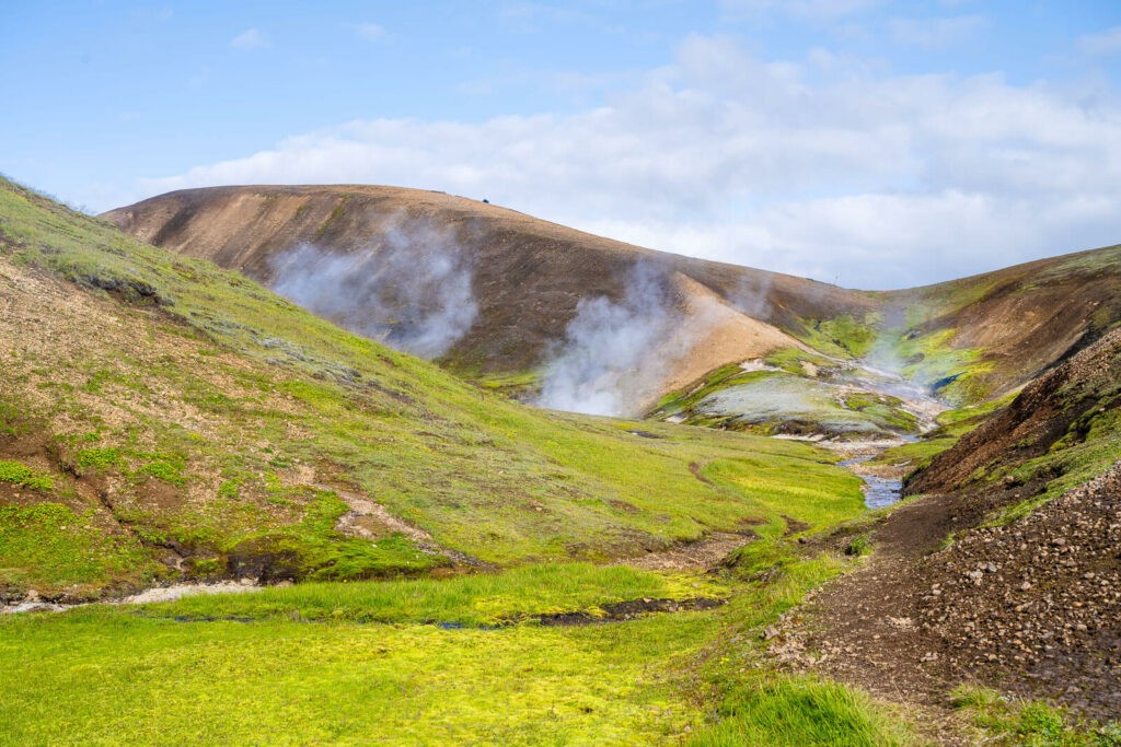 green fields and geothermal areas with fumaroles in the highlands of iceland