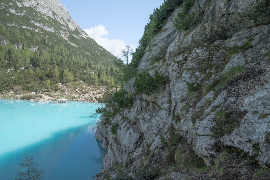 Wall of rock above the turquoise waters of a lake in the dolomiti 