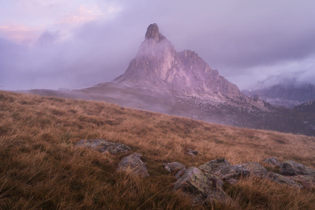 Early morning light and fog around the mountain Ra Gusela above pass Giau in the dolomites during a sunrise hike,