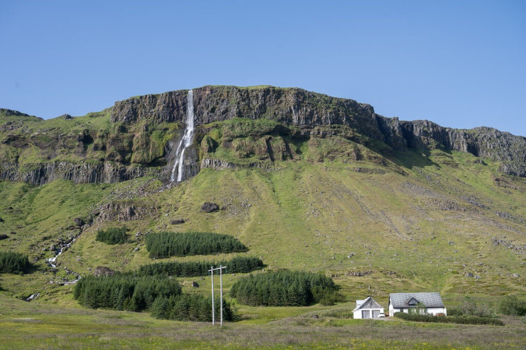 Bjarnarfoss waterfall with a small countryside house in the foreground