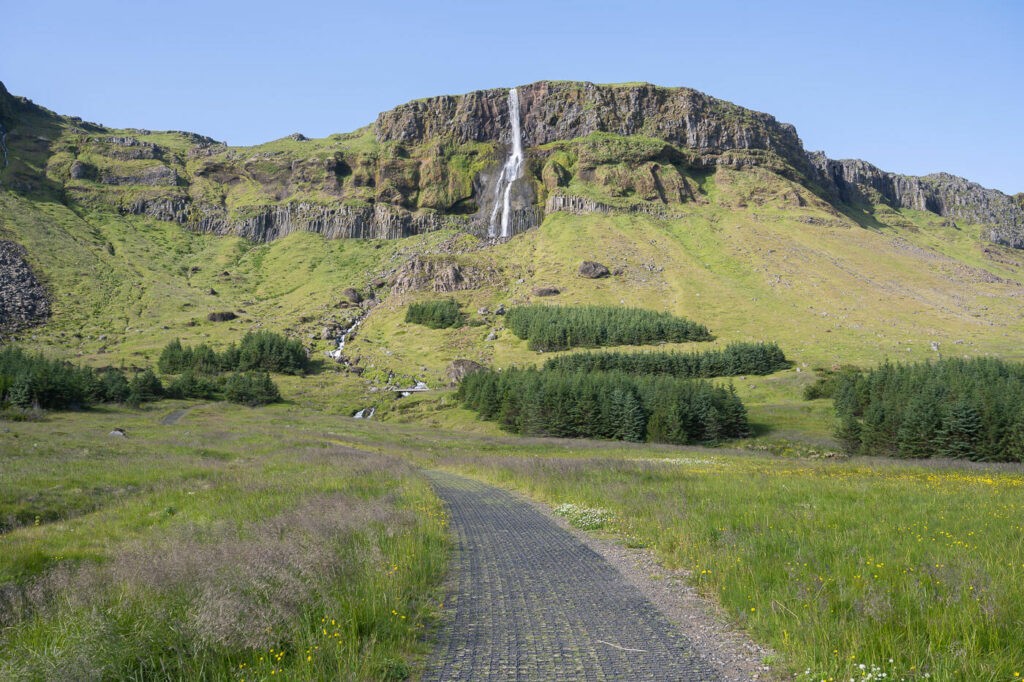 Hiking trail with Bjarnafoss in the background on a sunny day
